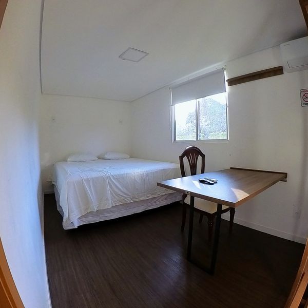 Suíte do Flat do Chef com cama de casal e mesa
