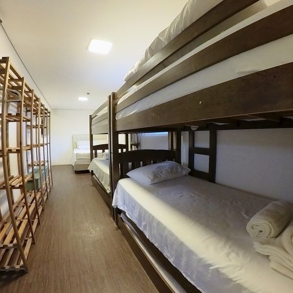 Quarto do Flat da Família com beliche, estante e cama de casal ao fundo
